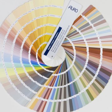 Ein runder Farbfächer mit spiralförmig aufgefächerten Farbmustern, der auf neutralem Hintergrund eine große Farbpalette von hellen bis zu dunklen Farbtönen zeigt.
