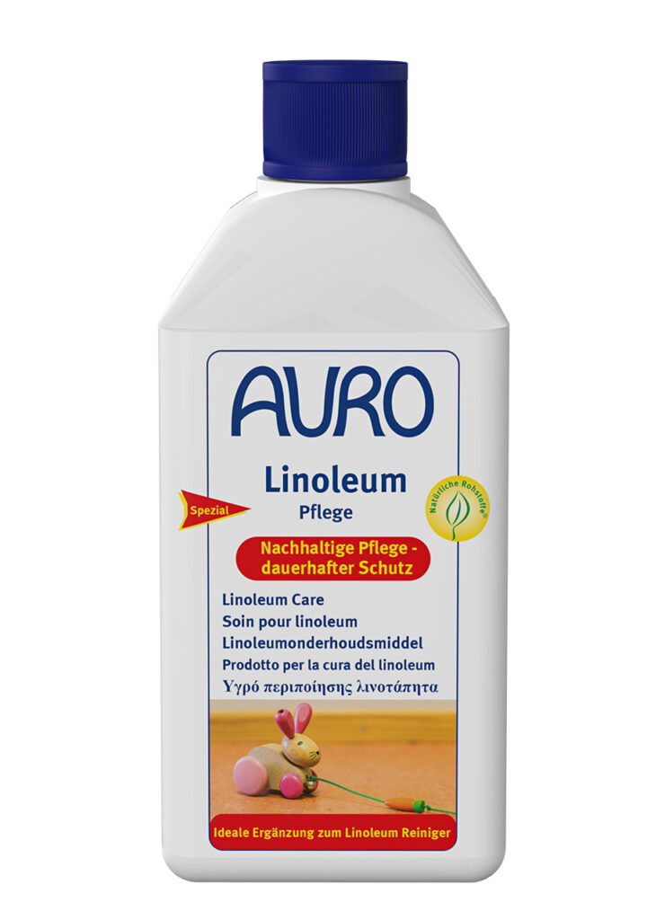 AURO Pflanzenchemie Linoleum-Pflege: Weiße Flasche mit blauem Verschluss, mehrsprachigem Etikett und rosa Spielzeugenten auf Holz. Umweltfreundliche Pflege für Linoleum – schonende, nachhaltige Reinigung und dauerhafter Schutz.